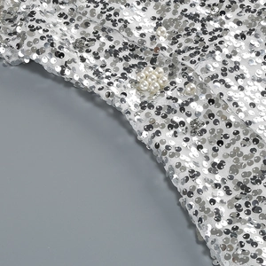 Dettaglio di paillettes argento, perle bianche e strass su tessuto a rete bianco