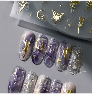 Detail of gold fairy moon nail stickers with butterfly and star motifs on purple nails