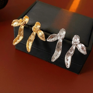 Macro detail of orchid petal earrings in gold and silver with textured metal finish