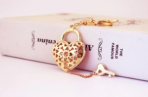 Detailed close-up of golden hollow heart lock keychain with small key on a book