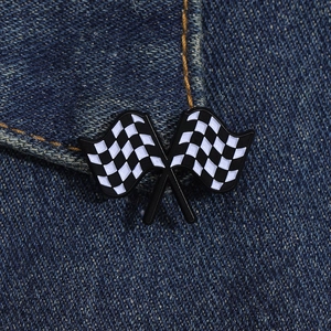 Close-up of racing checkered flag metal brooch pinned on dark blue denim fabric texture