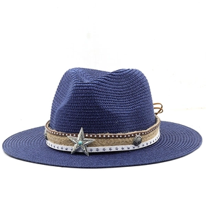 Detail of blue straw sun hat featuring turquoise star emblem and studded leather band