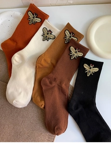 Detail of knitted ribbed socks featuring exquisite golden bee embroidery in various colors