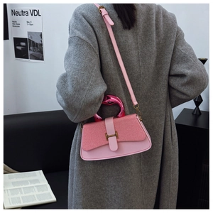 Close-up of pink leather crossbody bag with swan handle and golden H-shaped clasp