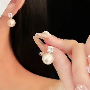 Elegant silver earrings with white round pearl and square cubic zirconia on dark background