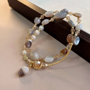Detail of layered retro bracelet with natural brown stones, crystal beads and pearls