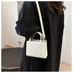Detail shot of white quilted PU leather bag with chevron pattern and gold-tone hardware