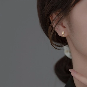 Close-up of elegant tulip-shaped silver stud earring with golden stem and crystal drop