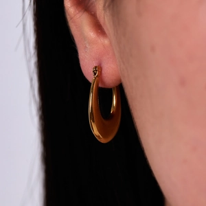 Close-up of a high-polished gold U-shaped earring worn by a model in French vintage style