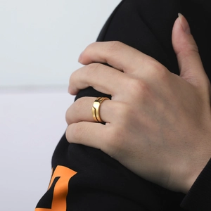 Close-up of a minimalist wide gold band ring worn on a finger with sharp metallic detail