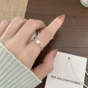 Minimalist 925 sterling silver pearl ring with crossing line design worn by a model