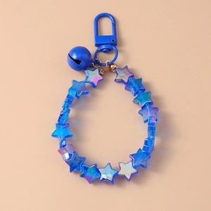Macro detail of blue iridescent star beads and bell pendant on a creative keychain