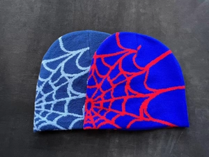 Detail of knitted beanie hats featuring jacquard spider web patterns in blue and red