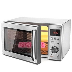 Pink heart-shaped silicone mold placed inside a modern silver microwave for baking