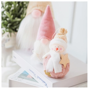 Pink velvet Christmas gnome and snowman plush ornaments displayed on vintage books