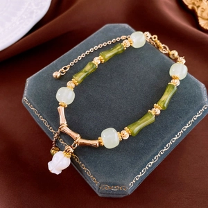 Detailed view of bamboo style bracelet with gold metal links and floral resin charms