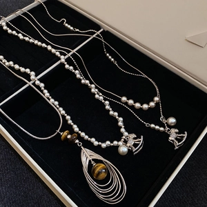 Close-up of pearl necklaces with a rocking horse and teardrop tiger eye pendants