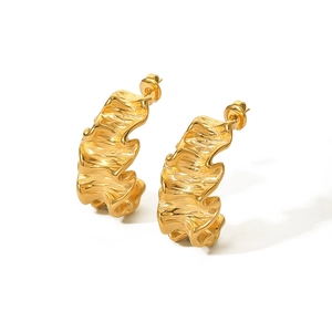 Macro shot of gold stainless steel hoop earrings with irregular wavy texture detail