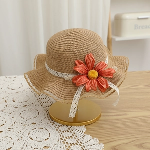 Détail d'un chapeau de paille tissé à la main avec fleur orange et rubans en dentelle