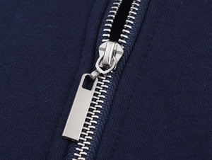Détail d'une fermeture éclair en métal argenté sur un sweat-shirt en tissu côtelé bleu marine