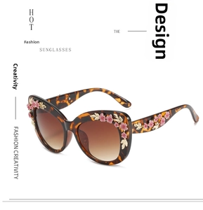 Macro shot of gold leaf and pink flower details on baroque tortoiseshell sunglasses