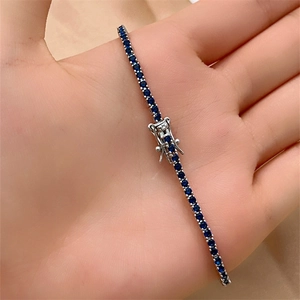 Detailed close-up of dark blue tennis bracelet with secure box clasp held in hand