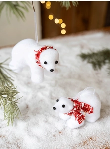 Detail of white flocked polar bear ornaments with red knitted scarves on a festive tree