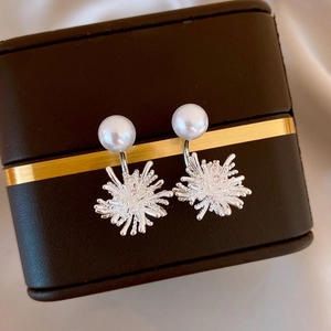 Macro view of 18k gold plated pearl and zircon firework earrings in a vintage jewelry box