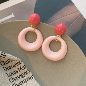 Boucles d'oreilles créoles en résine rose sur une assiette décorative en céramique