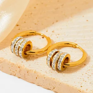 Golden hoop earrings with three zircon-encrusted rings on elegant satin background