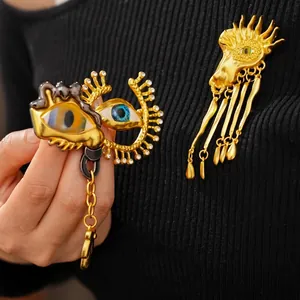 Vintage surrealist gold eye brooch with rhinestones and tassel charms on black fabric