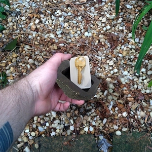 Realistic resin rock key hider box showing hidden compartment with a gold key inside