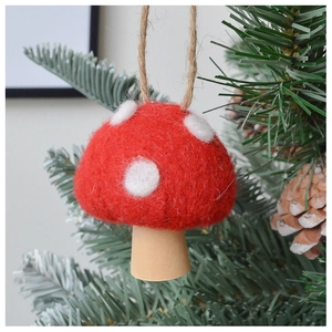 Detail of wool felt red mushroom ornament with white polka dots hanging on a Christmas tree