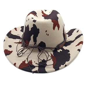 Close-up of cow print cowboy hat with brown leather band and metallic rivet details