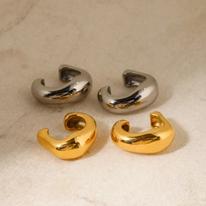 Detail of gold and silver thick rivet ear cuffs on textured stone surface with polished finish