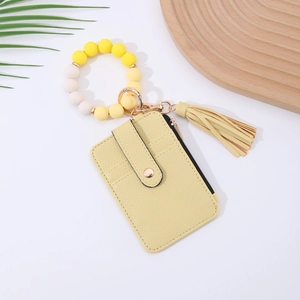 Detail of yellow pebbled leather card holder with silicone bead bracelet and tassel