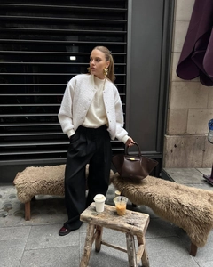 Close-up of stylish white fleece bomber jacket with brown leather bag and gold accessories