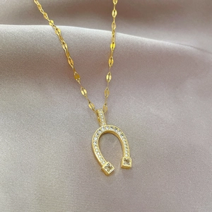Detail of gold horseshoe necklace with micro-pave crystals on grey silk background