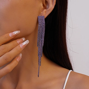 Macro detail of long purple tassel earrings with sparkling rhinestones worn by a model