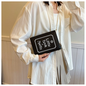 Detail of creative black book-shaped crossbody bag with Little Book of Spells print
