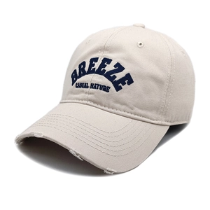 Dettaglio cappellino beige vintage con ricamo blu e bordo della visiera usurato