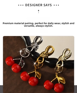 Detailed macro view of cherry resin bag charm showing polished metallic leaves and hardware