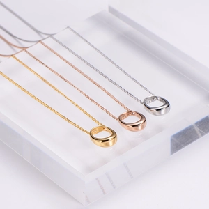 Minimalist polished metal ring necklaces in gold, rose gold and silver on display blocks