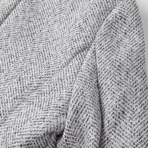 Macro shot of gray herringbone tweed fabric detail showing premium wool texture for skirt set