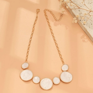 Detail of gold necklace with white round pendants and elegant vintage textured droplets