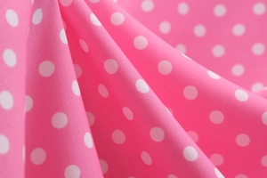 Detailed macro view of pink fabric with white polka dots showing textile texture and folds