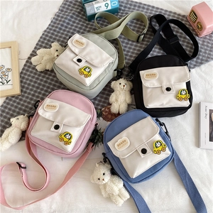 Détail de quatre sacs à bandoulière en toile colorée avec breloques d'ours en peluche