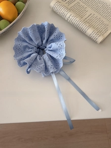 Close-up of light blue lace scrunchie with ribbons on a minimalist white desk