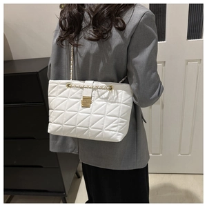 Détail du sac cabas blanc matelassé en similicuir avec chaîne dorée sur blazer gris