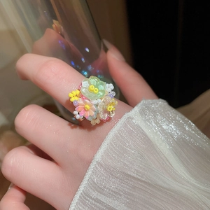 Dettaglio dell'anello a fiori in resina colorata con petali verdi e rosa sulla mano